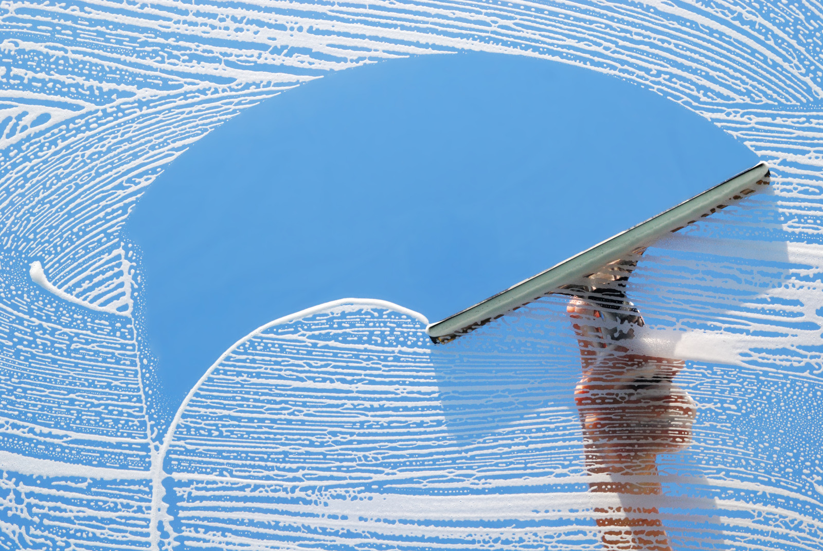 Squeegee wiping soap suds off window glass